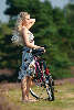 Pretty bicycle-girl portrait on the way blonde in heath-nature landscape,