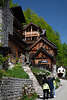 105710_Hallstatt urige Holzhuser Foto in grner Berghangkulisse mit Touristen vor Pfad Steintreppe Rundweg zur Soleleitung