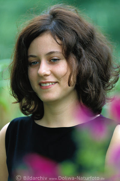 Girl face in black-hair portrait in garden-flowers laughing happy 